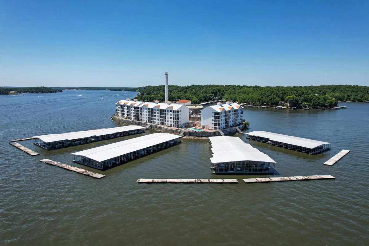 A scenic exterior view showcasing the waterfront property, marina docks, and picturesque lighthouse. The scene captures opportunities for boating, fishing, and exploring the lake, with tranquil water and lush greenery.
