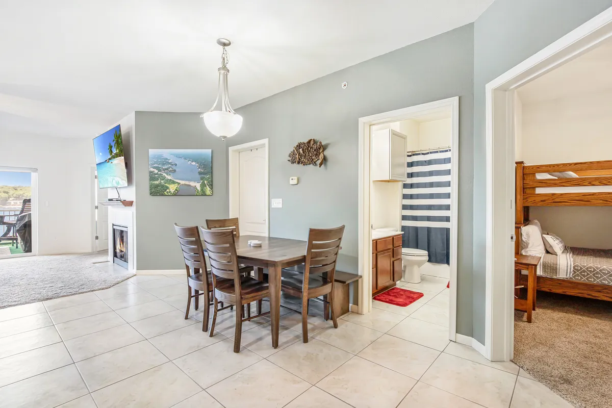 A cozy dining area with a table set for family meals, a bunk bed in the background, a large window providing natural light and scenic views, and a wall-mounted TV. The space feels warm and functional, perfect for sharing meals, playing games, or enjoying the view together.