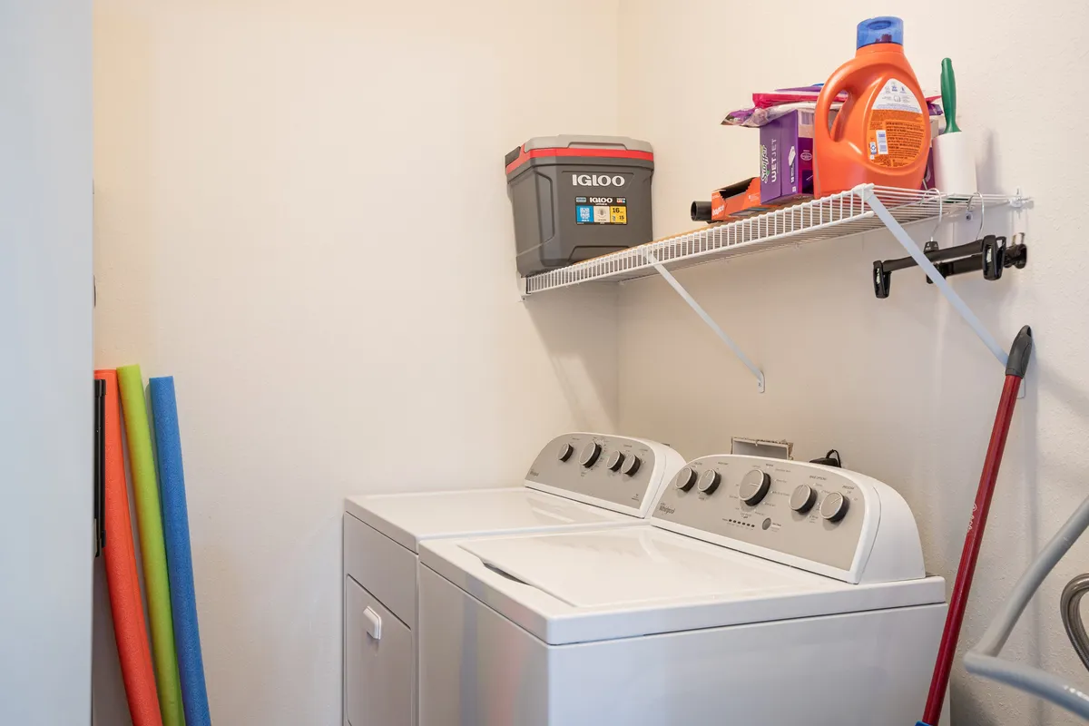 A practical laundry area with a washing machine and dryer, shelf stocked with cleaning supplies, ensuring guests can easily keep clothing fresh during their stay.