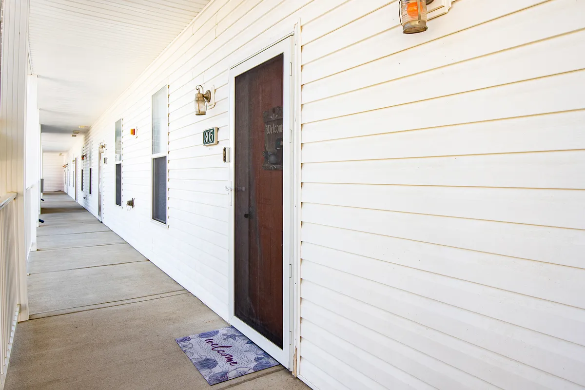 A close-up exterior view of a doorway with a welcome mat and light fixture, suggesting the primary entry point into the property. The scene feels inviting and approachable, emphasizing the ease of entry.