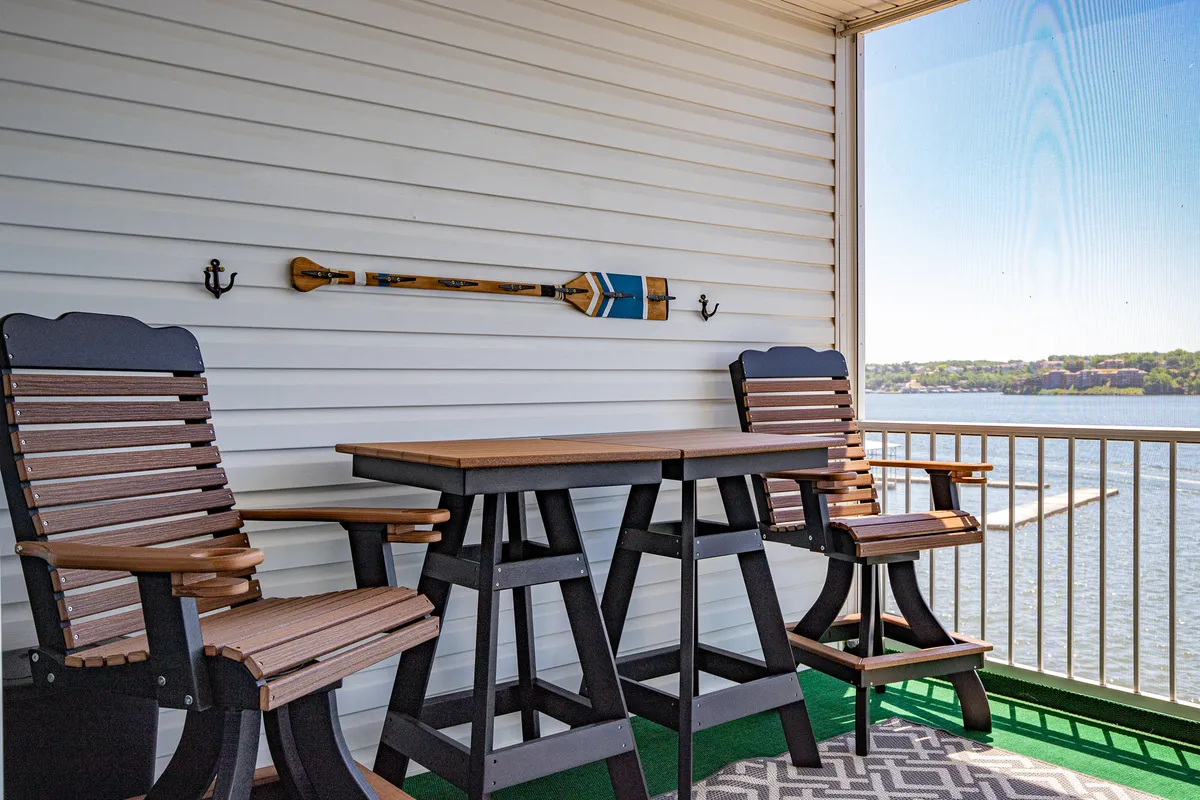 A tranquil veranda setup with wooden chairs and a table, decorative paddle, and direct water views. The mood is set for relaxing conversations and stargazing, with a cozy, intimate ambiance.