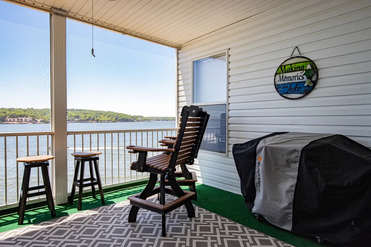 A serene lakeside veranda with wooden chairs and a barbecue grill, overlooking the water. The setting evokes relaxation and togetherness, ideal for lakeside grilling and gatherings as described in the section.