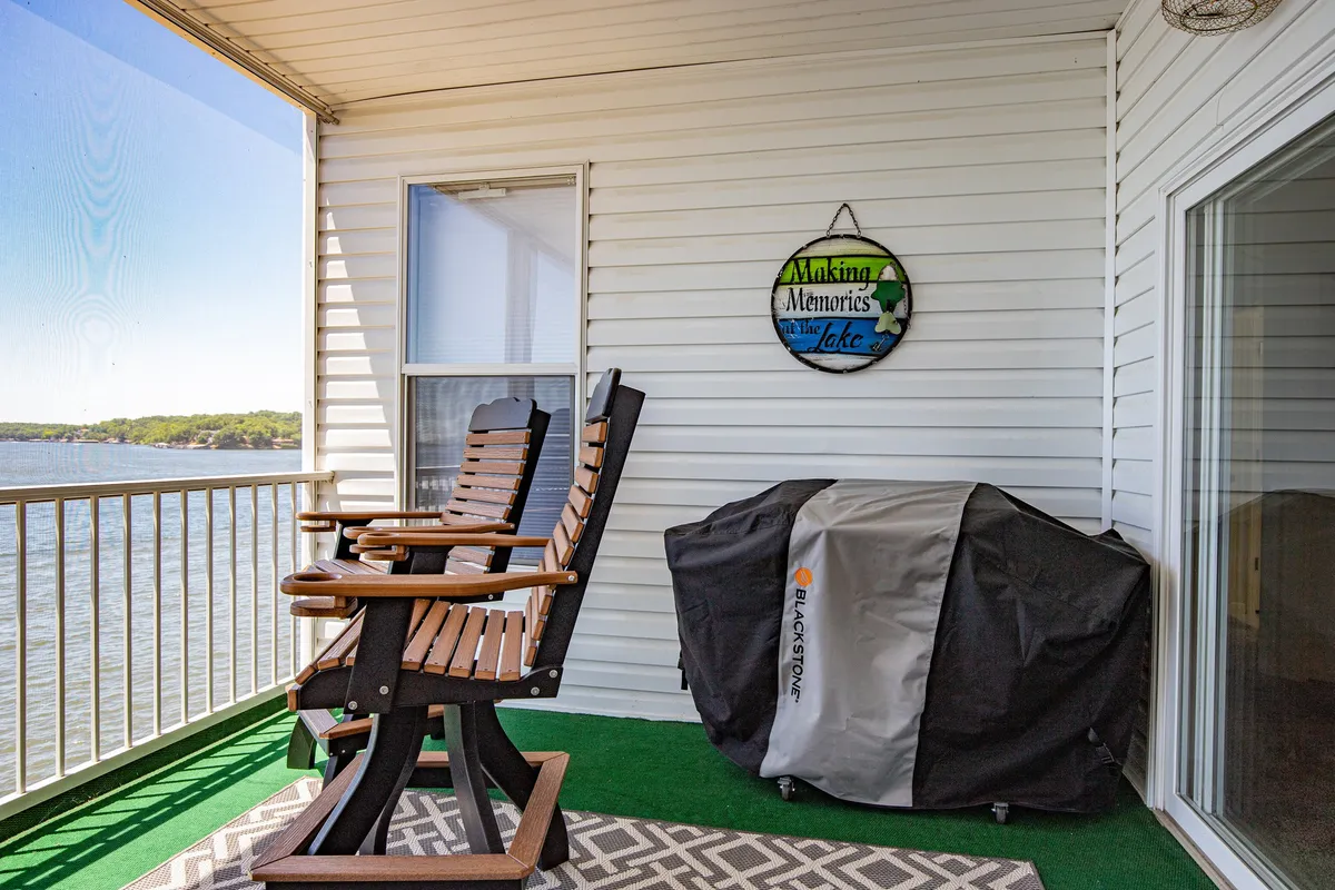 This serene exterior image shows rocking chairs on a lakeside balcony with a decorative sign, inviting groups to relax while taking in the water views. The space is ideal for quiet mornings, casual conversation, or evening wind-downs after a day of activity.