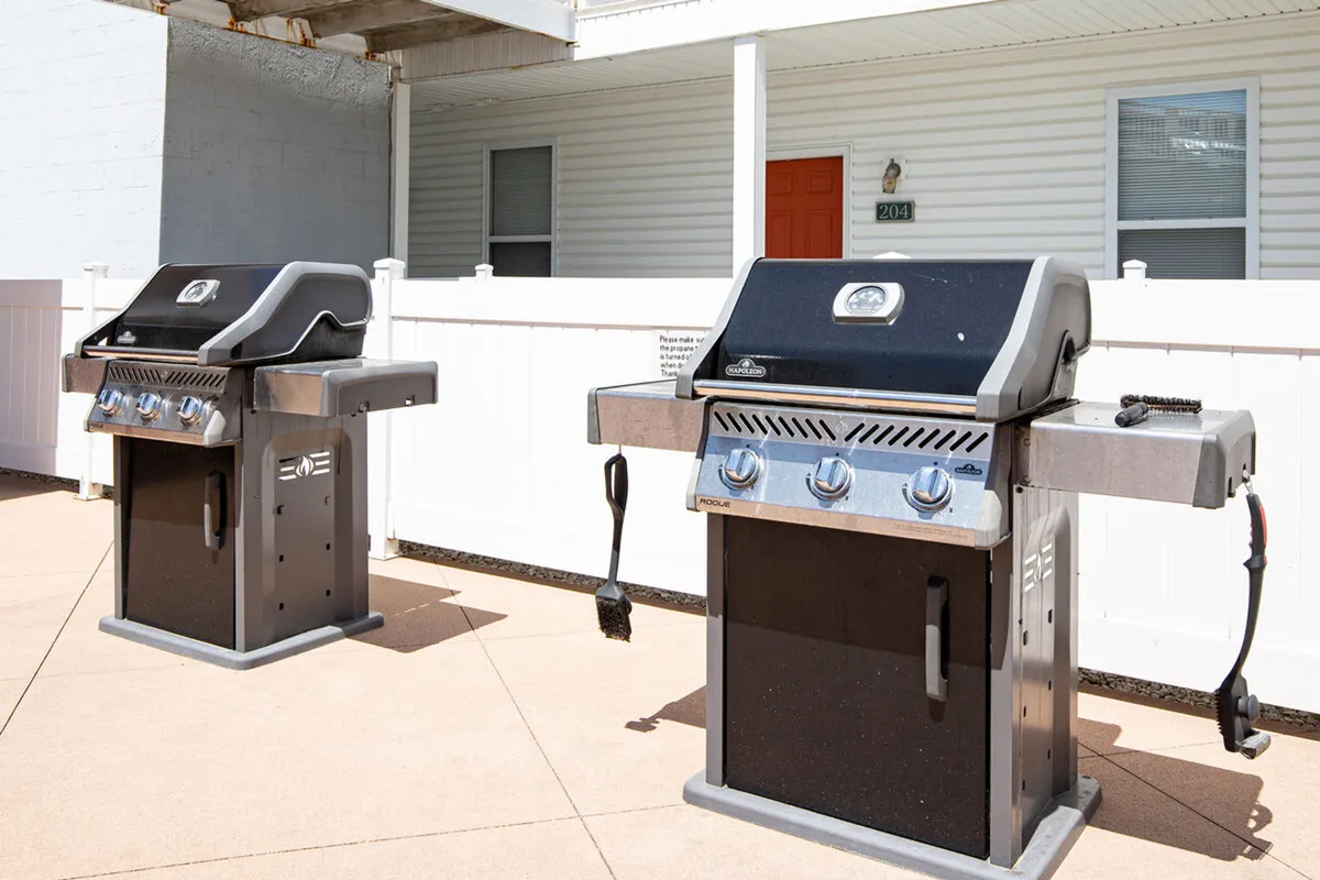 This exterior image features two gas grills, a white fence, and a vibrant red door, setting the stage for outdoor cookouts. The grill area is ready for casual, festive barbecues, supporting group dining and socializing just steps from the lake.