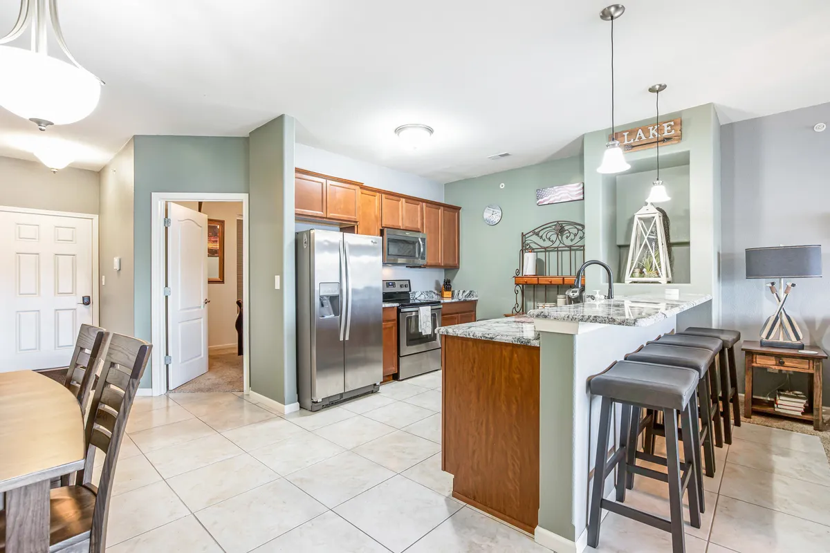A spacious, modern kitchen featuring a central island, stainless steel appliances, and warm wood cabinetry. The adjacent dining table and decorative details create a welcoming atmosphere for home-cooked meals and social gatherings.